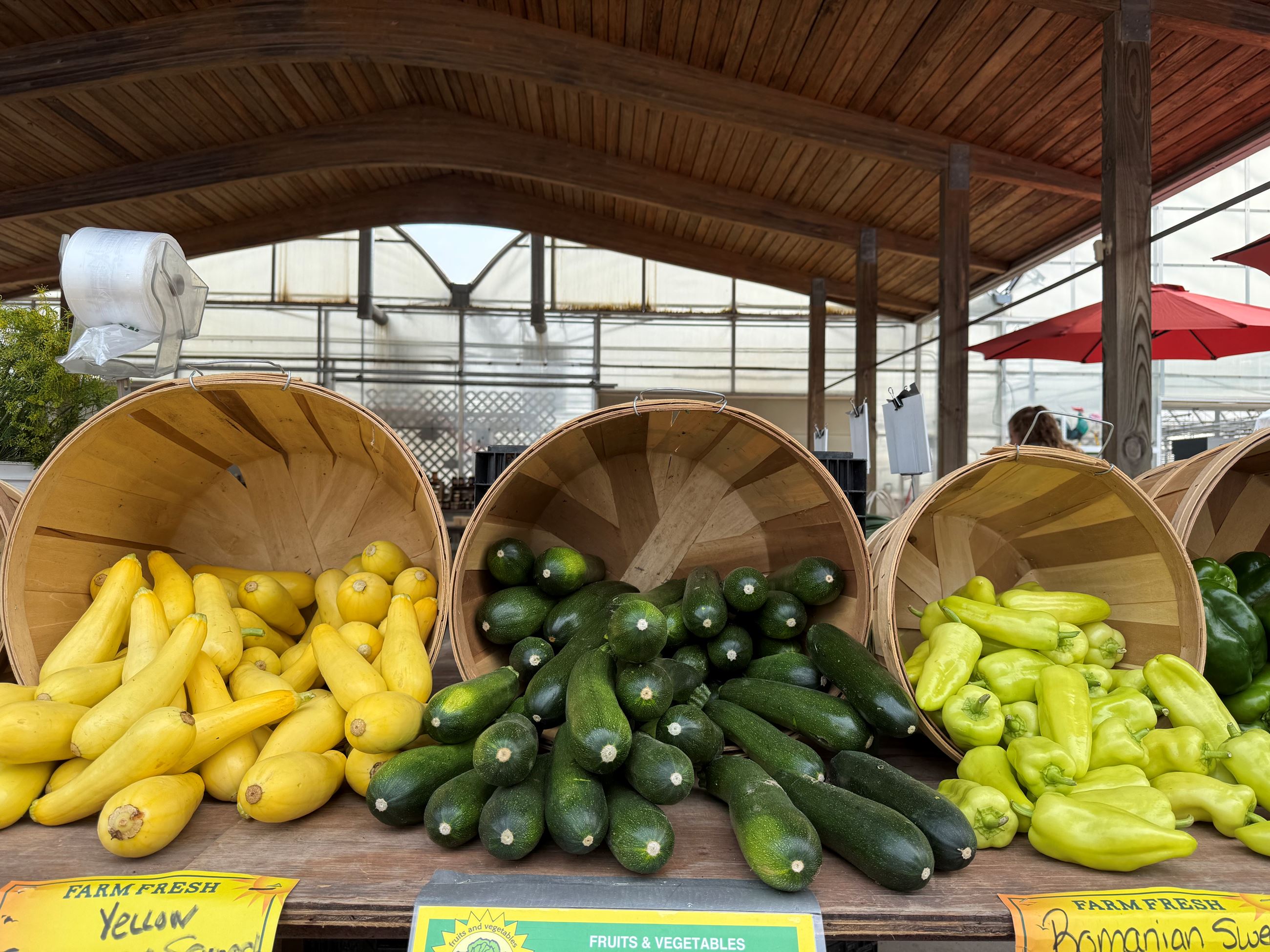 Photo of a farm market vegetable stand with buckets on their sides to show off of various squashes 