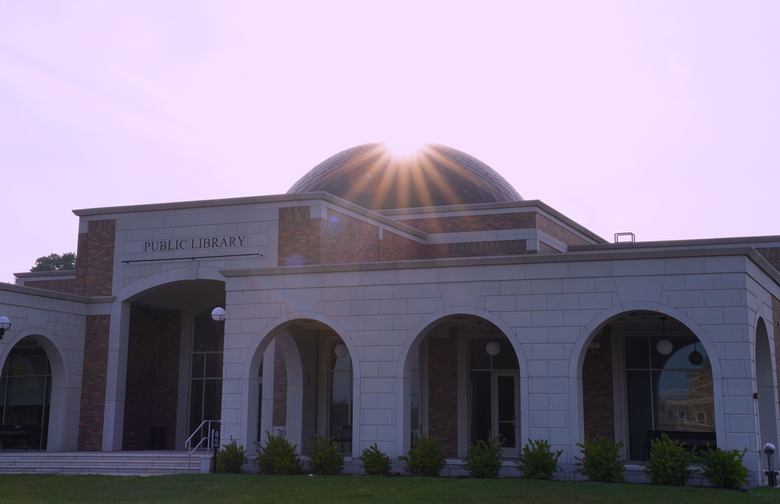 Photo of the north branch library in the summer sunrise with the sun peeking over the domed ceiling